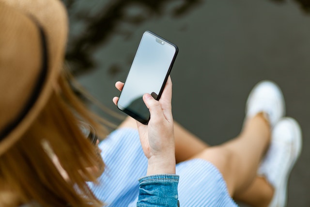 Kobieta trzymająca telefon mająca dostęp do materiałów językowych