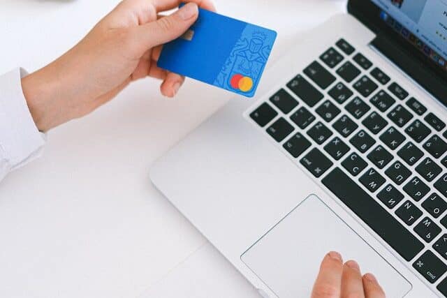Osoba trzymająca laptopa i kartę płatniczą przygotowuje się do płatności online